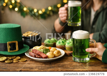Friends toasting with green ale for Saint Patricks Day. Festive table with corned beef, cupcakes and lucky charms. Friends toasting with green ale for Saint Patricks Day. Festive table with corned beef, cupcakes and lucky charms. 136619778