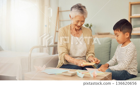 一位老婦人在家中接受安寧療護，與孫子女共度時光：寧靜的家庭時光，一起享受摺紙的樂趣。 136620656