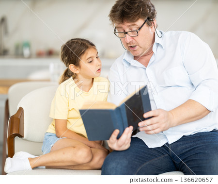 Father reads book to little cute daughter, spend leisure enjoy good life hobby and pastime at home. Fatherhood, upbringing, children development 136620657