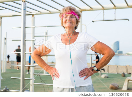Old woman doing fitness exercises outdoors 136620658