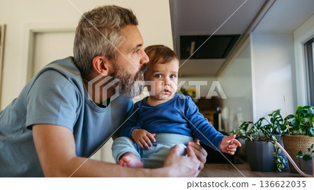 Father with little toddler son looking out of window. 136622035