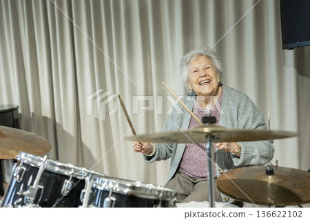 Senior woman enjoying her hobby playing drums. Senior woman enjoying her hobby playing drums. 136622102