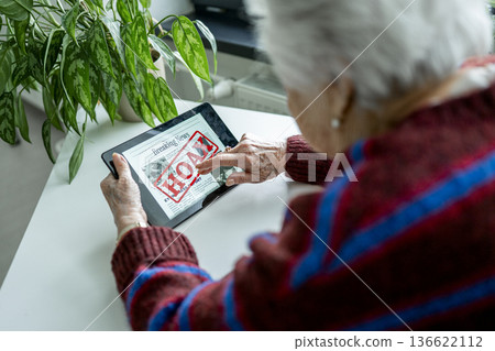 Old person recognizing fake news on digital tablet. Old person recognizing fake news on digital tablet. 136622112