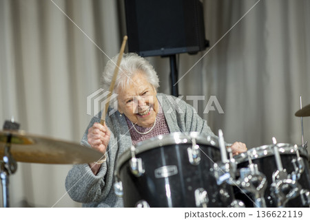 Senior woman enjoying her hobby playing drums. Senior woman enjoying her hobby playing drums. 136622119