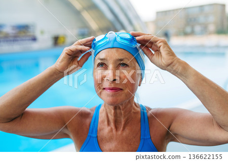 Older female swimmer getting ready for regular fitness swimming. 136622155