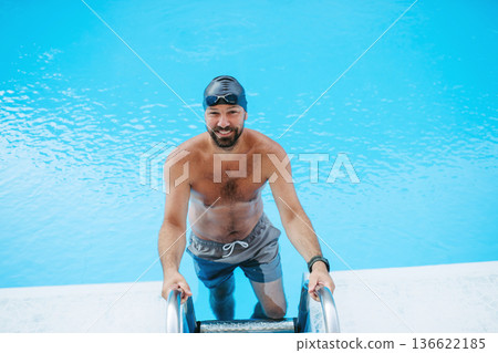 Male swimmer is preparing for swim in pool. Male swimmer is preparing for swim in pool. 136622185