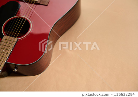 Close-up of a red acoustic guitar showing strings and fretboard, illustrating guitar maintenance, adjusting and changing strings for repair and care. Close-up of a red acoustic guitar showing strings and fretboard, illustrating guitar maintenance, adjusting and changing strings for repair and care. 136622294
