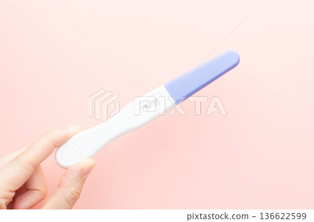 Pregnant woman holding a positive urine pregnancy test on pink background. Pregnancy test kit measure hCG levels in urine. Pregnant woman holding a positive urine pregnancy test on pink background. Pregnancy test kit measure hCG levels in urine. 136622599