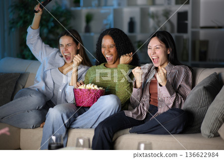 Excited diverse friends watching tv content at home in the night 136622984