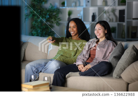 Diverse happy couple watching tv in the night at home Diverse happy couple watching tv in the night at home 136622988