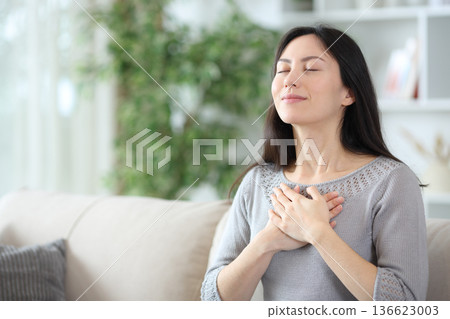 Single asian woman doing breathing exercises at home Single asian woman doing breathing exercises at home 136623003