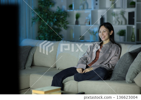 Single happy asian woman watching tv in the night Single happy asian woman watching tv in the night 136623004