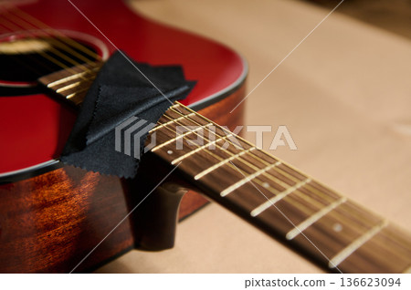Red Acoustic Guitar With Cleaning Cloth on Strings for Maintenance and Repair Red Acoustic Guitar With Cleaning Cloth on Strings for Maintenance and Repair 136623094