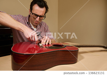 Master Adjusting Guitar Strings: Man Changing Acoustic Guitar Strings for Repair and Maintenance Master Adjusting Guitar Strings: Man Changing Acoustic Guitar Strings for Repair and Maintenance 136623131