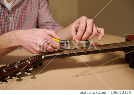 Man Changing Guitar Strings With Pliers During Guitar Maintenance and Repair Man Changing Guitar Strings With Pliers During Guitar Maintenance and Repair 136623139