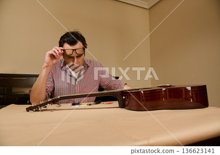 Man Adjusting Guitar Strings at Home Workshop - Guitar Maintenance and Repair 136623141
