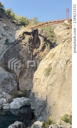 A red metal bridge over a mountain river. High quality photo A red metal bridge over a mountain river. High quality photo 136623331