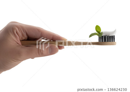 Hand holding a sustainable bamboo toothbrush with green mint toothpaste applied, representing eco-friendly oral care and zero waste living Hand holding a sustainable bamboo toothbrush with green mint toothpaste applied, representing eco-friendly oral care and zero waste living 136624230