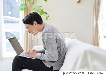 Asian man operating a computer with bad posture 136624467