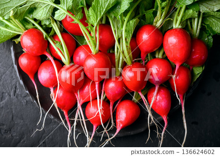 Fresh radishes on black plate on dark surface Fresh radishes on black plate on dark surface 136624602