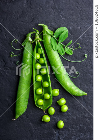 Green peas in pods on dark textile surface in top view 136624619