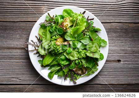 Green salad leaves arranged on white plate in minimal style Green salad leaves arranged on white plate in minimal style 136624626