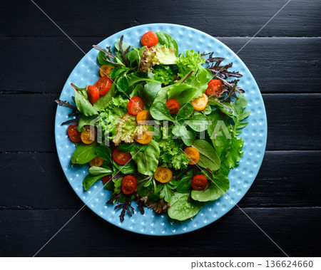 Mixed salad greens with cherry tomatoes on blue plate Mixed salad greens with cherry tomatoes on blue plate 136624660