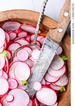Radish slices in wooden bowl with kitchen knife Radish slices in wooden bowl with kitchen knife 136624670