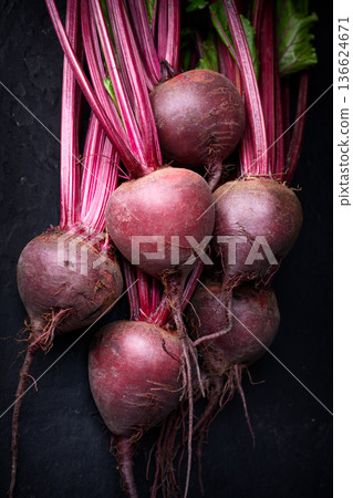 Raw beetroot bunch with leaves on dark surface Raw beetroot bunch with leaves on dark surface 136624671