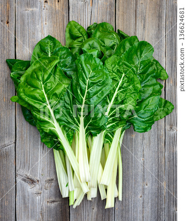 Swiss chard leaves with white stems arranged on wooden background Swiss chard leaves with white stems arranged on wooden background 136624681