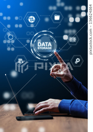 User interacts with digital data storage icons on a laptop screen in a workspace setting 136624864