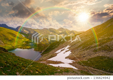 mountain lake in alpine summer landscape at sunset. beautiful view surrounded with clouds on a blue sky in evening light. fresh water, snow and rocky slopes. remote highlands adventures under rainbow mountain lake in alpine summer landscape at sunset. beautiful view surrounded with clouds on a blue sky in evening light. fresh water, snow and rocky slopes. remote highlands adventures under rainbow 136624942