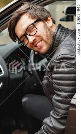 Man sits in car with glasses, ready to drive on a sunny day in an urban area Man sits in car with glasses, ready to drive on a sunny day in an urban area 136624946