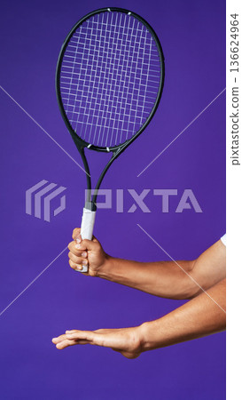 Tennis player prepares to serve with racket against purple background during practice 136624964