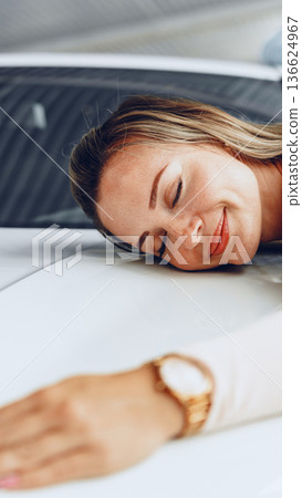 Woman enjoying the feeling of a car hood in a garage on a sunny day 136624967