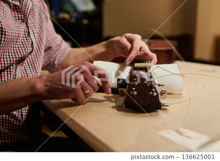 Man Changing Guitar Strings and Tuning Headstock During Guitar Maintenance and Repair Man Changing Guitar Strings and Tuning Headstock During Guitar Maintenance and Repair 136625001