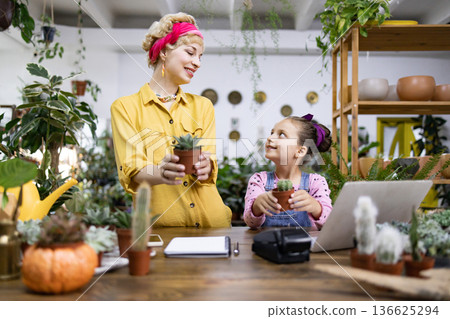 A mother and daughter share a special moment while working with succulents in a plant shop A mother and daughter share a special moment while working with succulents in a plant shop 136625294