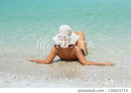 back view of young beautiful woman with coconut relaxing at sunny tropical beach back view of young beautiful woman with coconut relaxing at sunny tropical beach 136625714