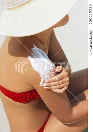 Sunscreen woman. Woman applying sunscreen on tanned skin 136625720