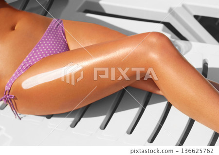 Closeup on female hand applying sun screen creme on leg Closeup on female hand applying sun screen creme on leg 136625762