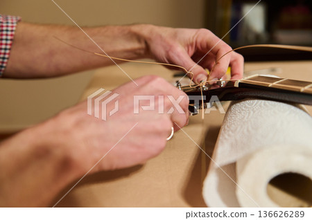Man Changing Guitar Strings Close-Up Repair and Maintenance of Acoustic Guitar Headstock Man Changing Guitar Strings Close-Up Repair and Maintenance of Acoustic Guitar Headstock 136626289