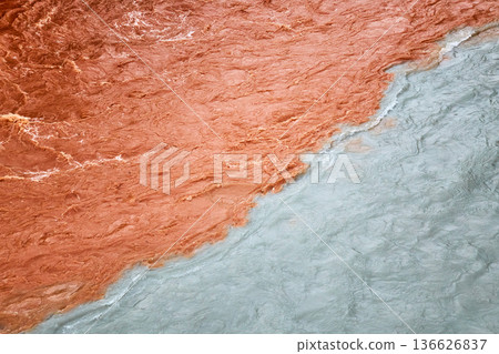 Two rivers meeting with distinct colors, one muddy brown and the other clear blue. Confluence of waters illustrating natural contrast. Two rivers meeting with distinct colors, one muddy brown and the other clear blue. Confluence of waters illustrating natural contrast. 136626837