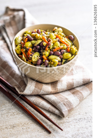 Fresh salad with edamame beans in bowl on checkered napkin. 136626895