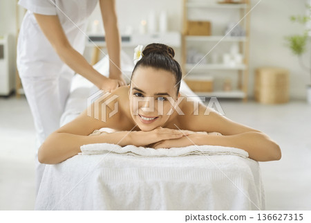 Smiling woman enjoying relaxing back massage at spa wellness center on table Smiling woman enjoying relaxing back massage at spa wellness center on table 136627315