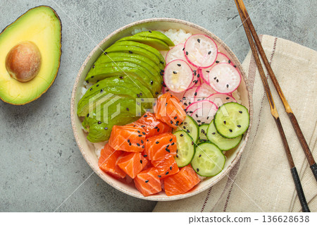 Salmon poke bowl with avocado, radish, cucumber and rice on grey background top view 136628638