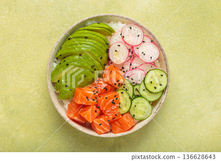 Salmon poke bowl with avocado, radish, cucumber and rice on green background top view 136628643