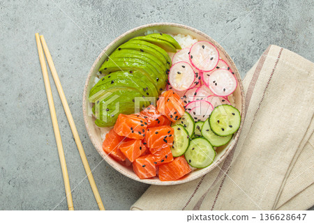 Salmon poke bowl with avocado, radish, cucumber and rice on grey background top view 136628647