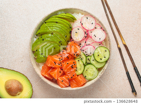 Salmon poke bowl with avocado, radish, cucumber and rice on light beige background top view 136628648