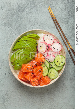Salmon poke bowl with avocado, radish, cucumber and rice on grey background top view Salmon poke bowl with avocado, radish, cucumber and rice on grey background top view 136628649