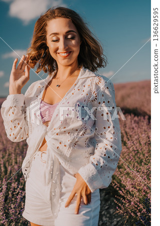 Lavender woman summer smiling young woman posing in a blooming purple lavender field wearing white stylish summer clothes Lavender woman summer smiling young woman posing in a blooming purple lavender field wearing white stylish summer clothes 136629595